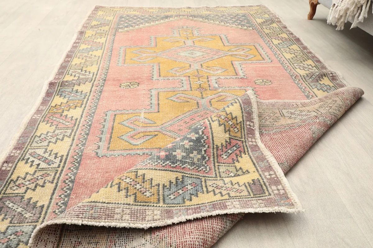 The vintage rug partially folded, showing the flexibility of its wool and cotton construction.