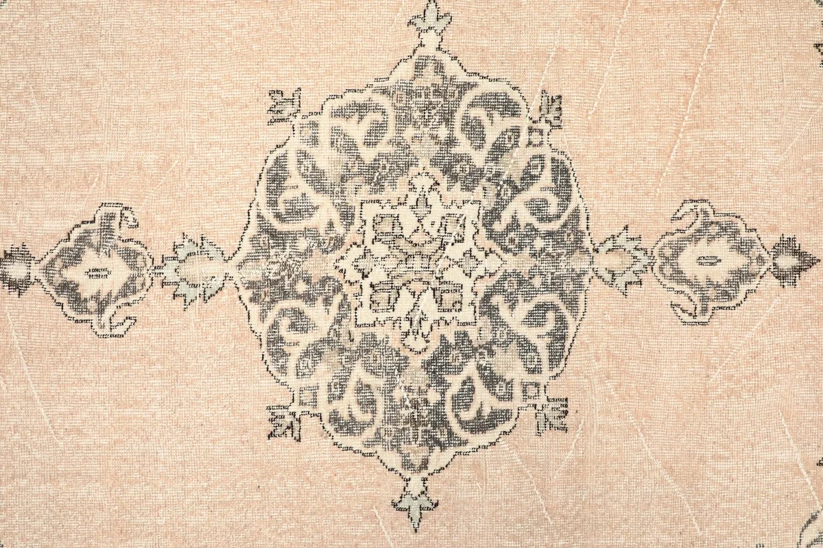 Close-up of the central medallion motif in charcoal and beige on the rug