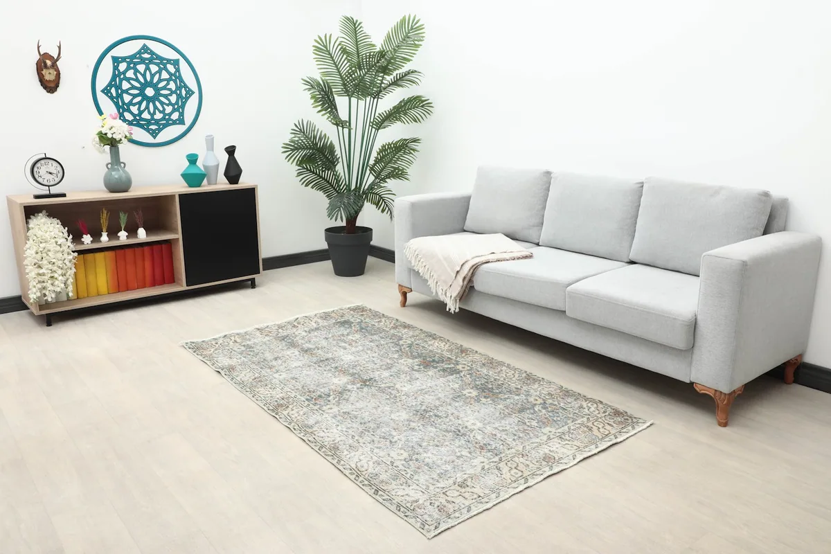 Full room view showing the small blue floral rug in a living space with a sofa