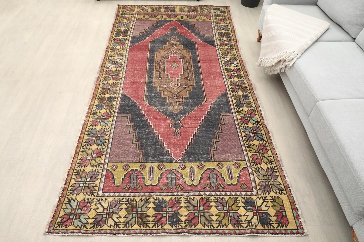 Vintage Anatolian rug in a room setting, showing its full length next to a sofa.