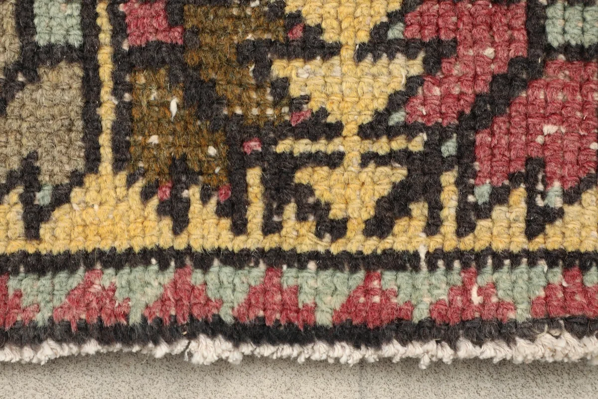 Close-up detail of the hand-knotted wool pile texture and colors in the rug's border.
