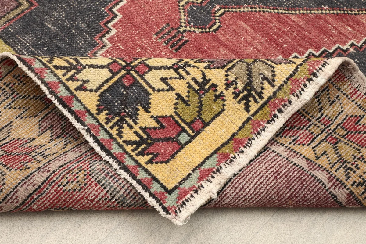 Folded corner of the rug revealing the cotton foundation and reverse side of the knots.