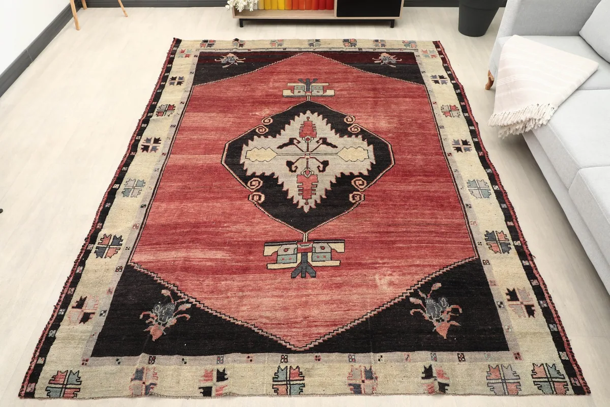 Vintage red Anatolian rug displayed in a bright room setting with a sofa