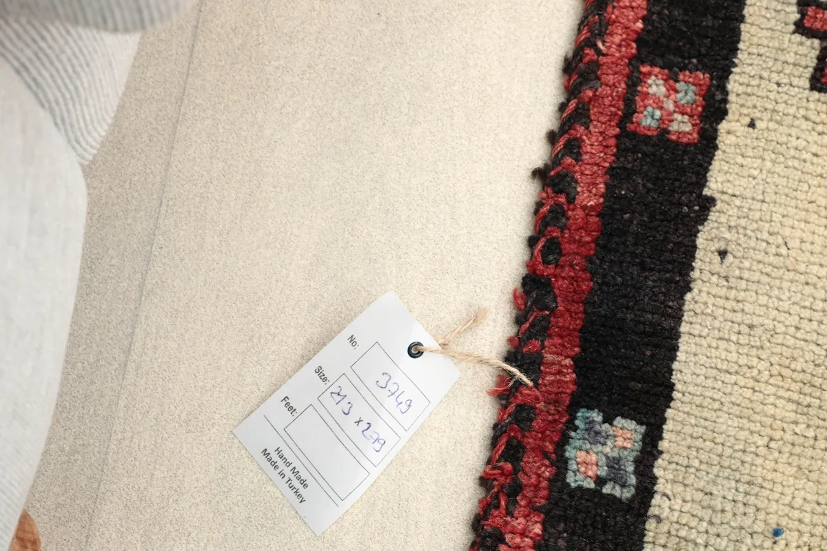 View of the rug's back with a product tag, showing the hand-knotted construction