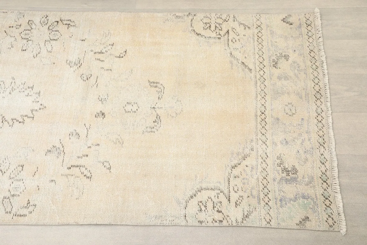 Close-up of one end of the cream runner rug, showing the faded gray and charcoal patterns.