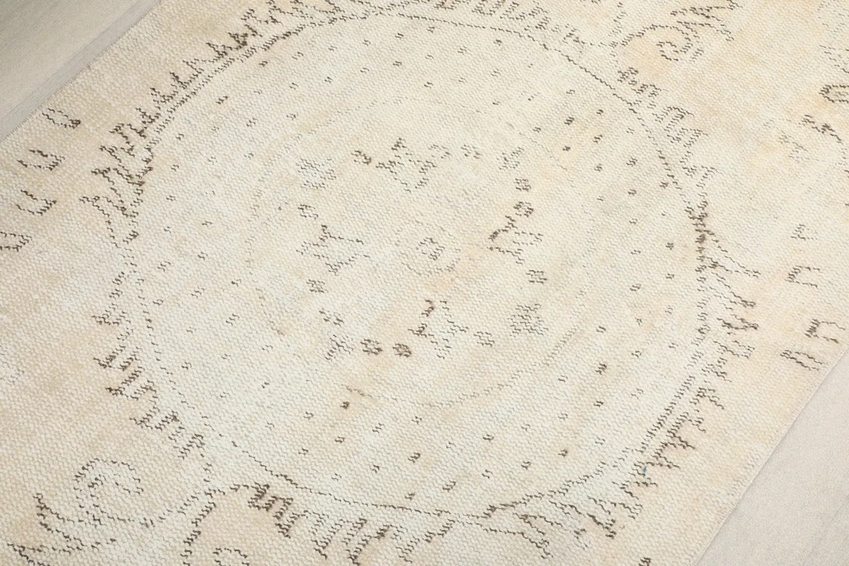Detailed view of the central medallion motif in muted gray and charcoal tones on the cream field.