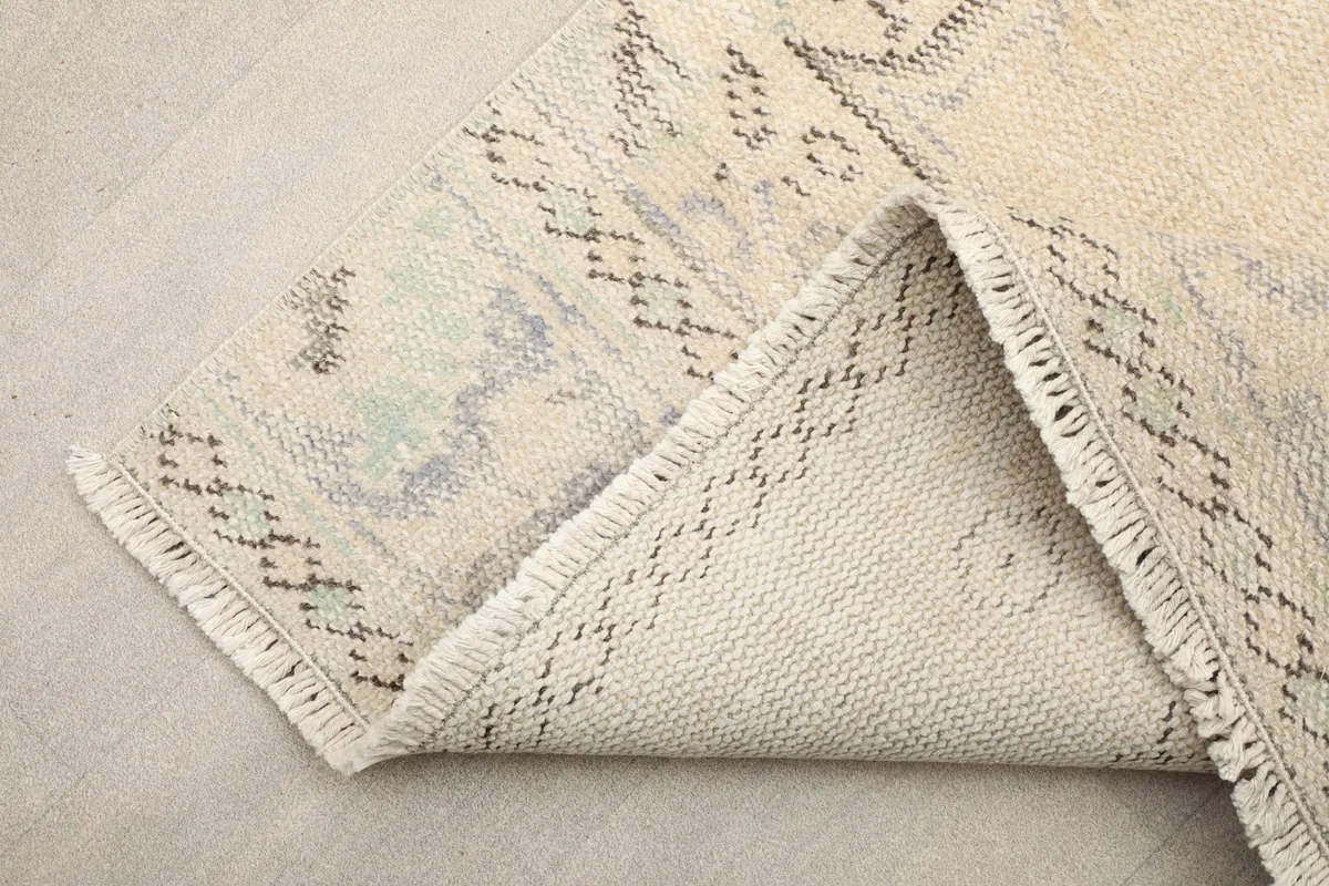 View of the back of the rug, folded to show the cotton foundation and fine knotting.