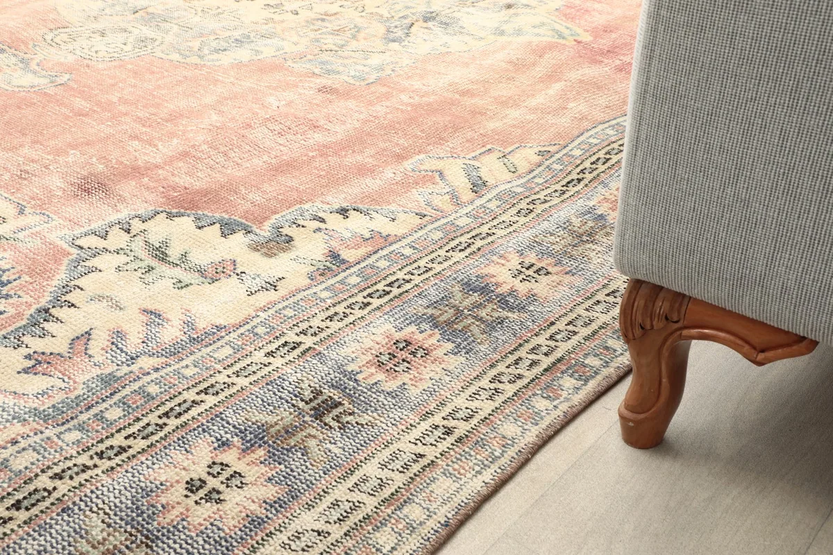 Close-up of the rug's border next to a furniture leg, showing the low pile and pattern