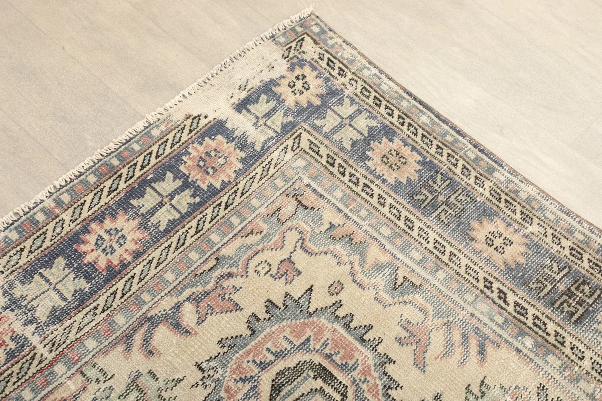 Corner detail of the vintage rug, showing geometric patterns and colors in the border