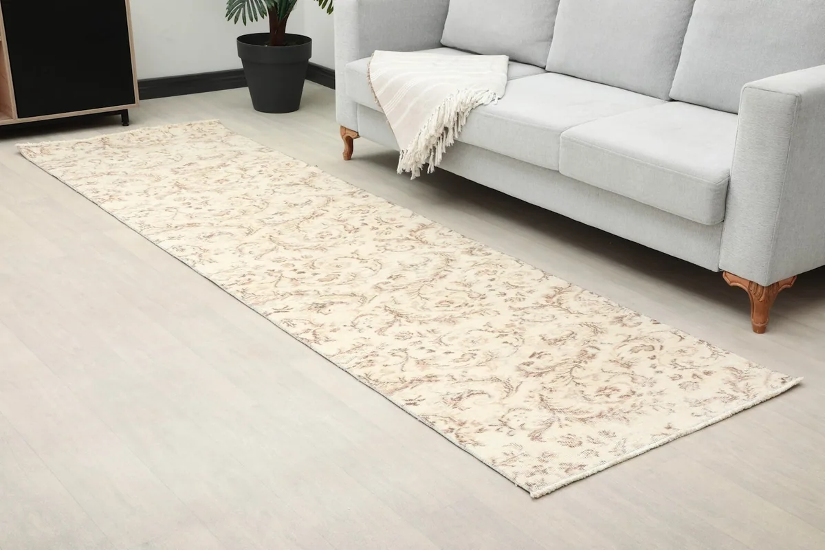 Close-up room view of the floral patterned runner rug extending from under a light gray sofa.