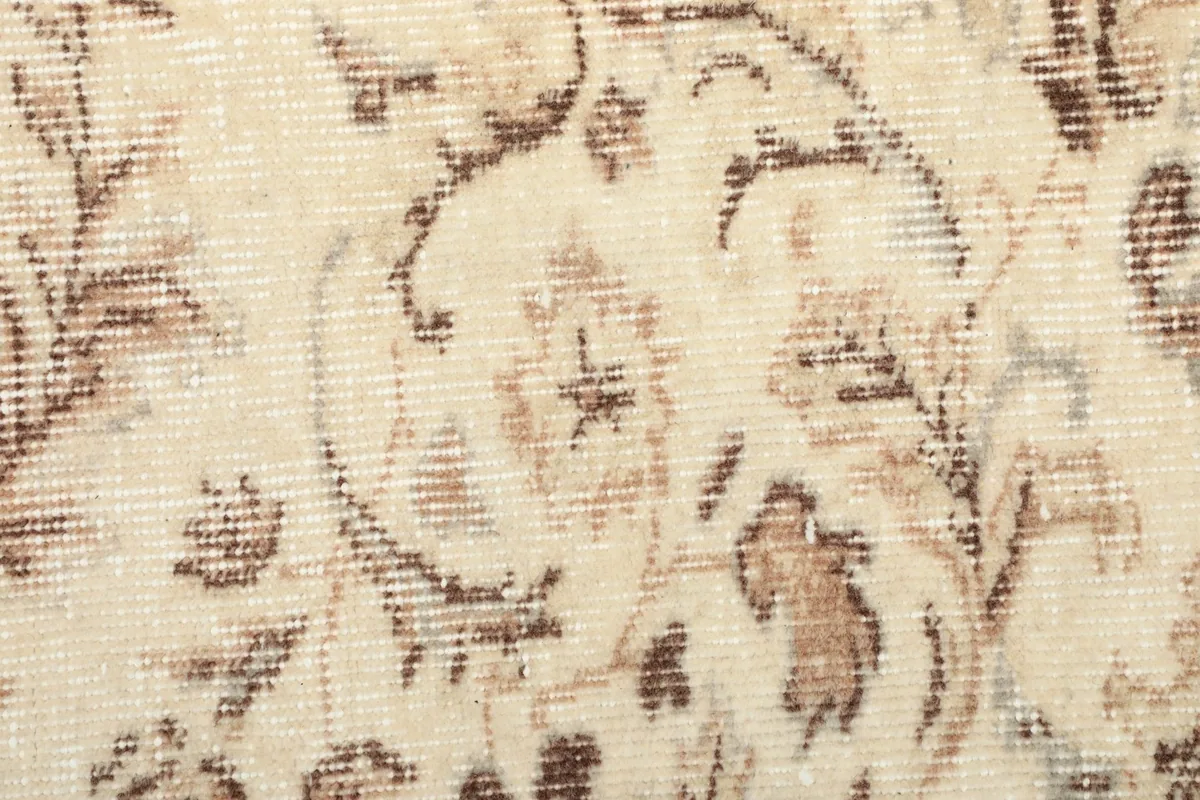 Close-up detail of the hand-knotted wool pile, revealing the varied tan and brown floral elements.