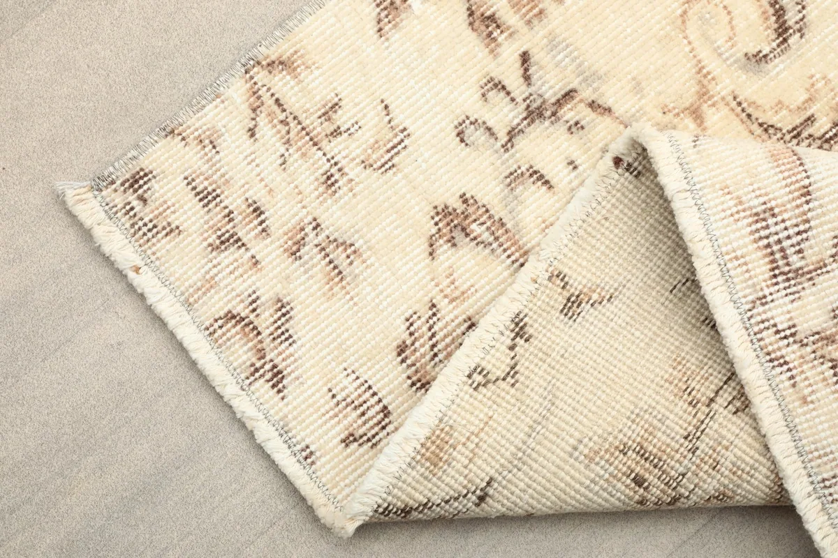Corner of the runner rug folded back to display the reverse side and cotton foundation.
