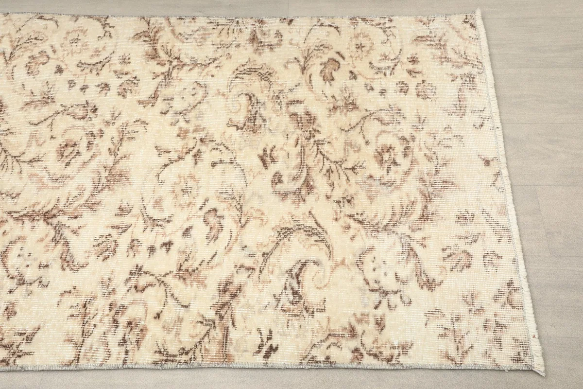 Overhead view showcasing the ivory field and tan-brown floral motifs of the hand-knotted runner.