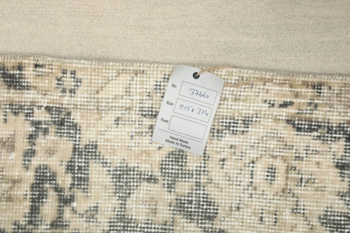 Overhead view of the rug's reverse side with a tag showing size and origin