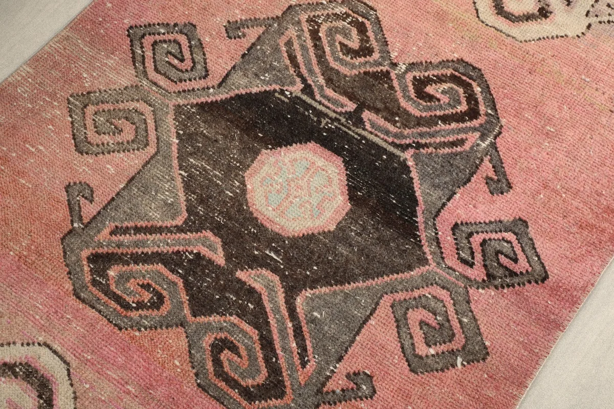 Angled close-up of a geometric motif, emphasizing the hand-knotted wool pile texture and color shifts