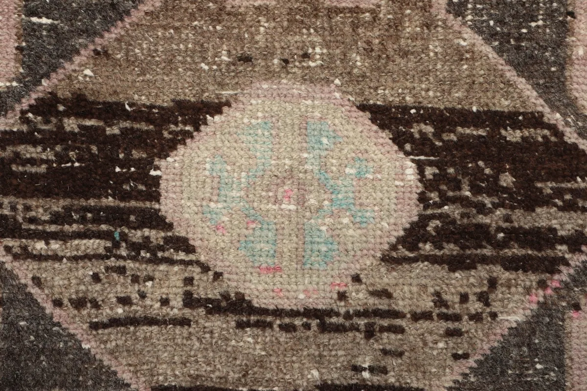 Extreme close-up of the wool pile and central motif detail, showing the intricate knotting and color variation