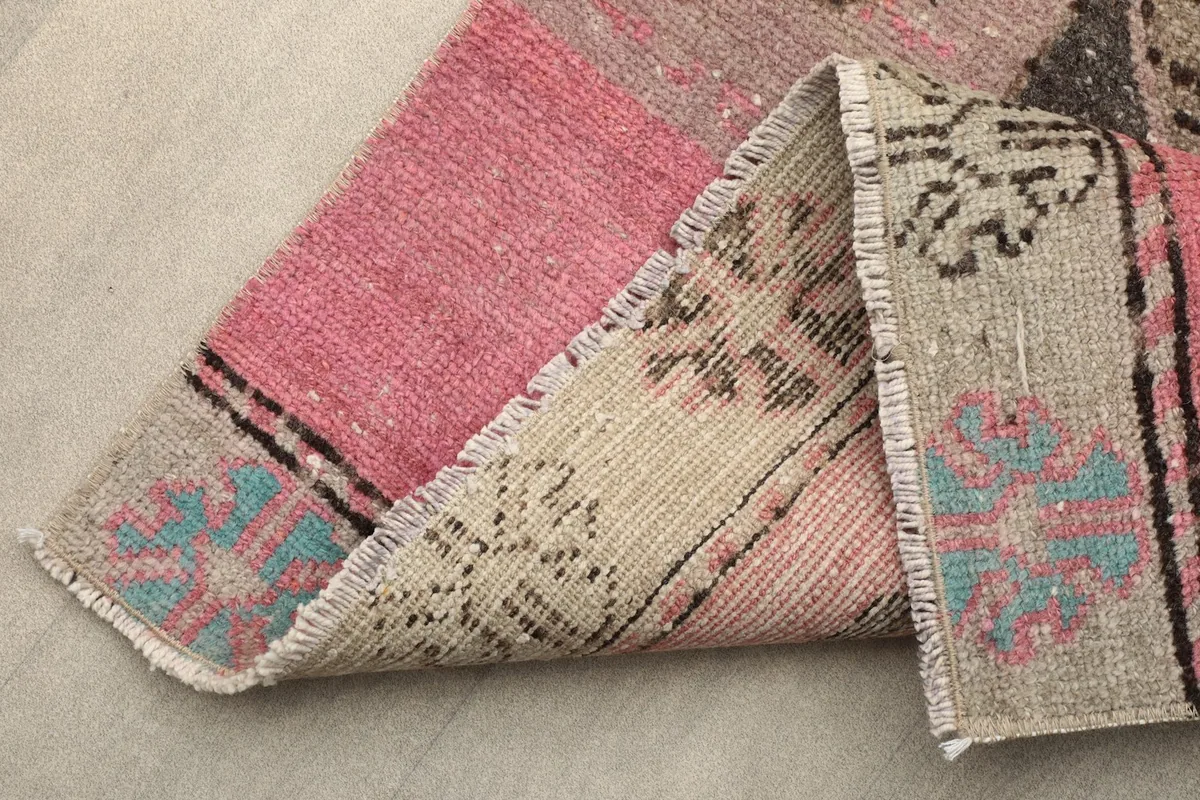Folded corner of the runner rug, revealing the back of the rug and the fringed edges