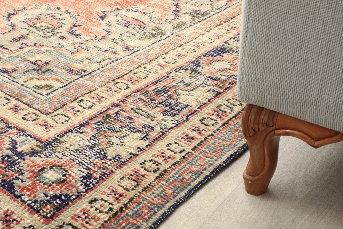Detail of the rug's border next to a sofa leg, showing its integration into a room
