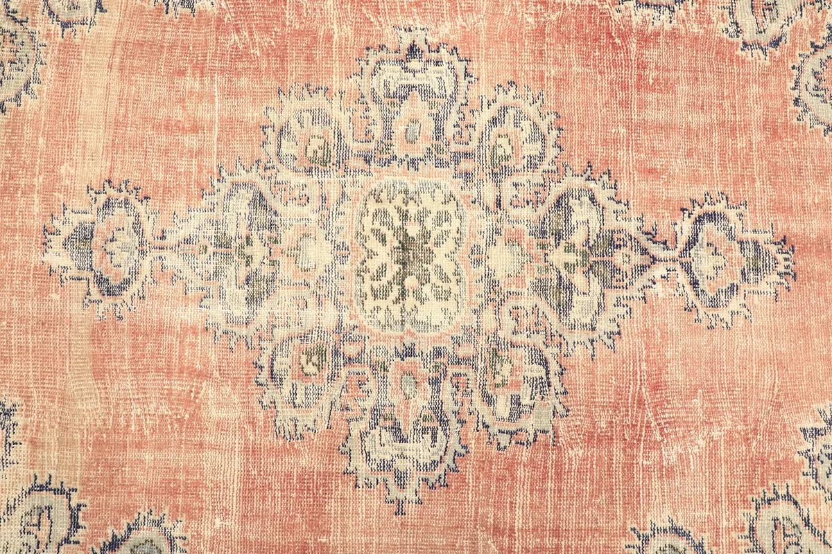 Close-up of the central medallion and surrounding floral motifs on the rust field