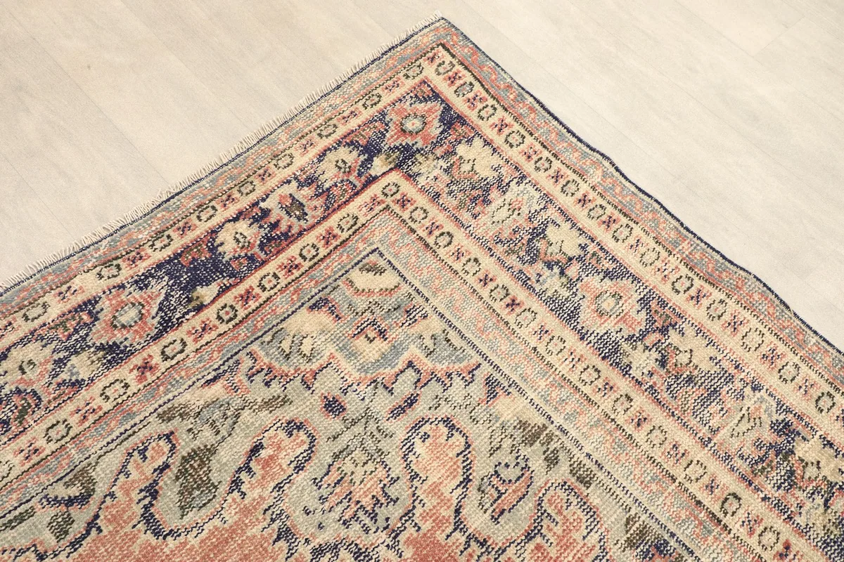 Corner detail showing the patterned navy and beige border of the hand-knotted rug