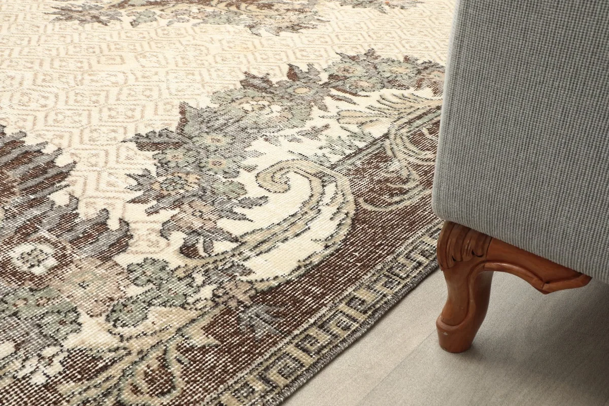 Close-up of the rug's border pattern next to a furniture leg in a room setting