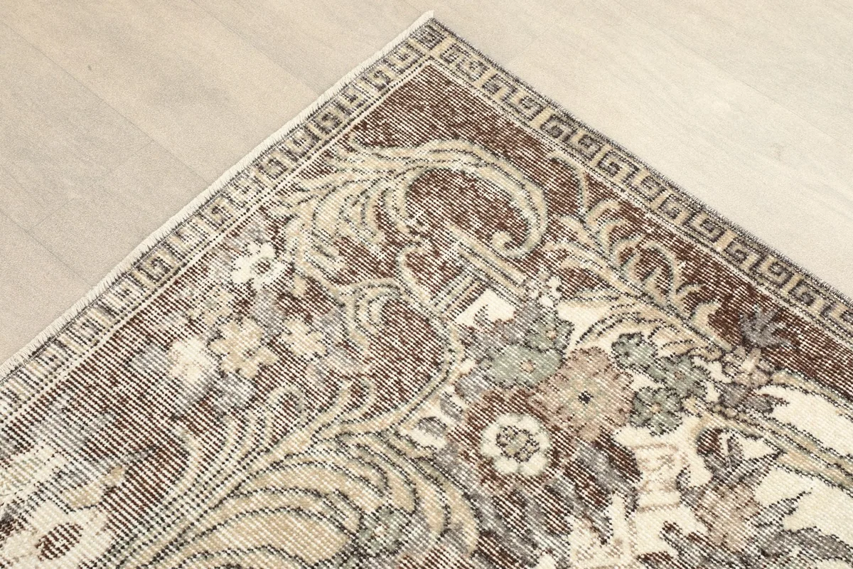 Detail of the brown border with floral and geometric patterns in the rug's corner