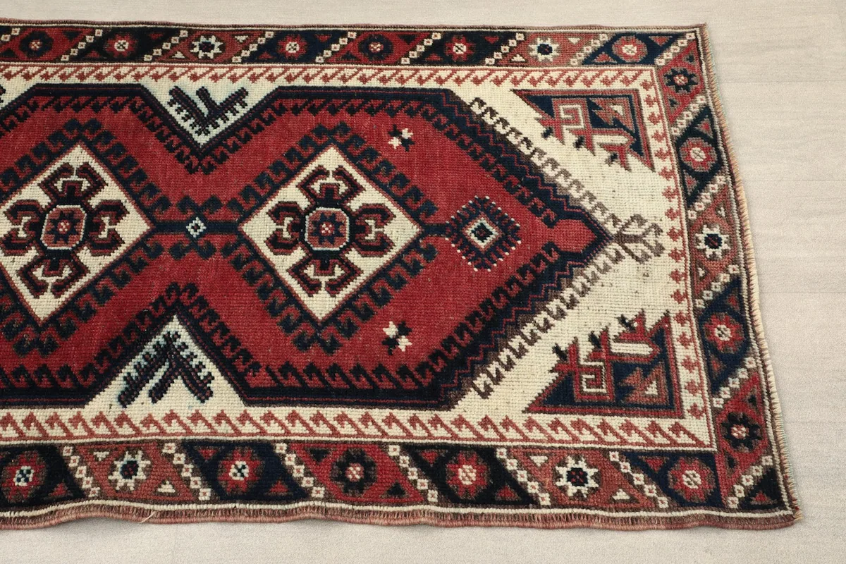 Close-up of the rug's end, highlighting the red, ivory, and navy geometric motifs