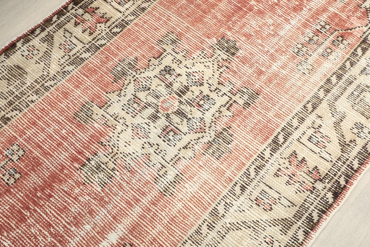 Detailed view of the central medallion and faded rose field of the rug