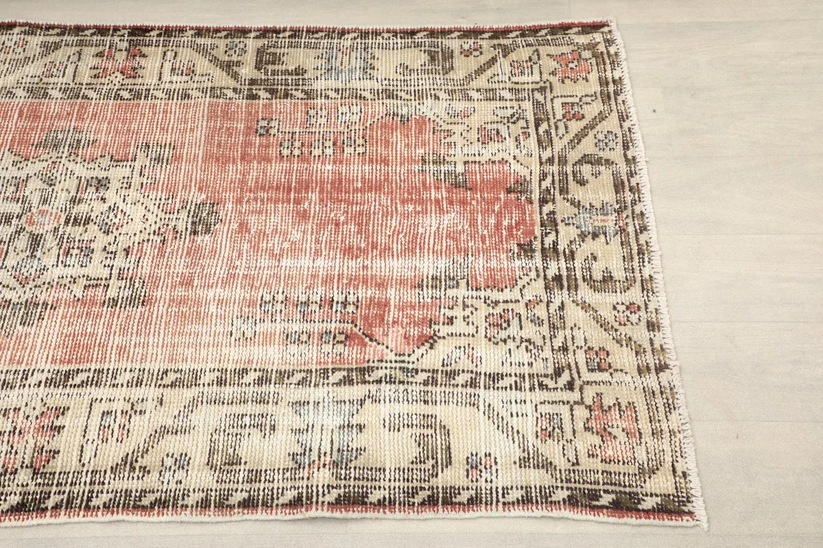 Close-up detail of the beige border with charcoal geometric motifs on the rug's right side