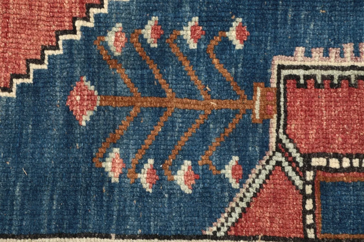 Detail of a tribal tree-like motif within the blue field of the rug