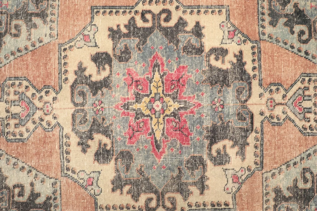 Detailed view of the central medallion with pink, yellow, blue, and black colors
