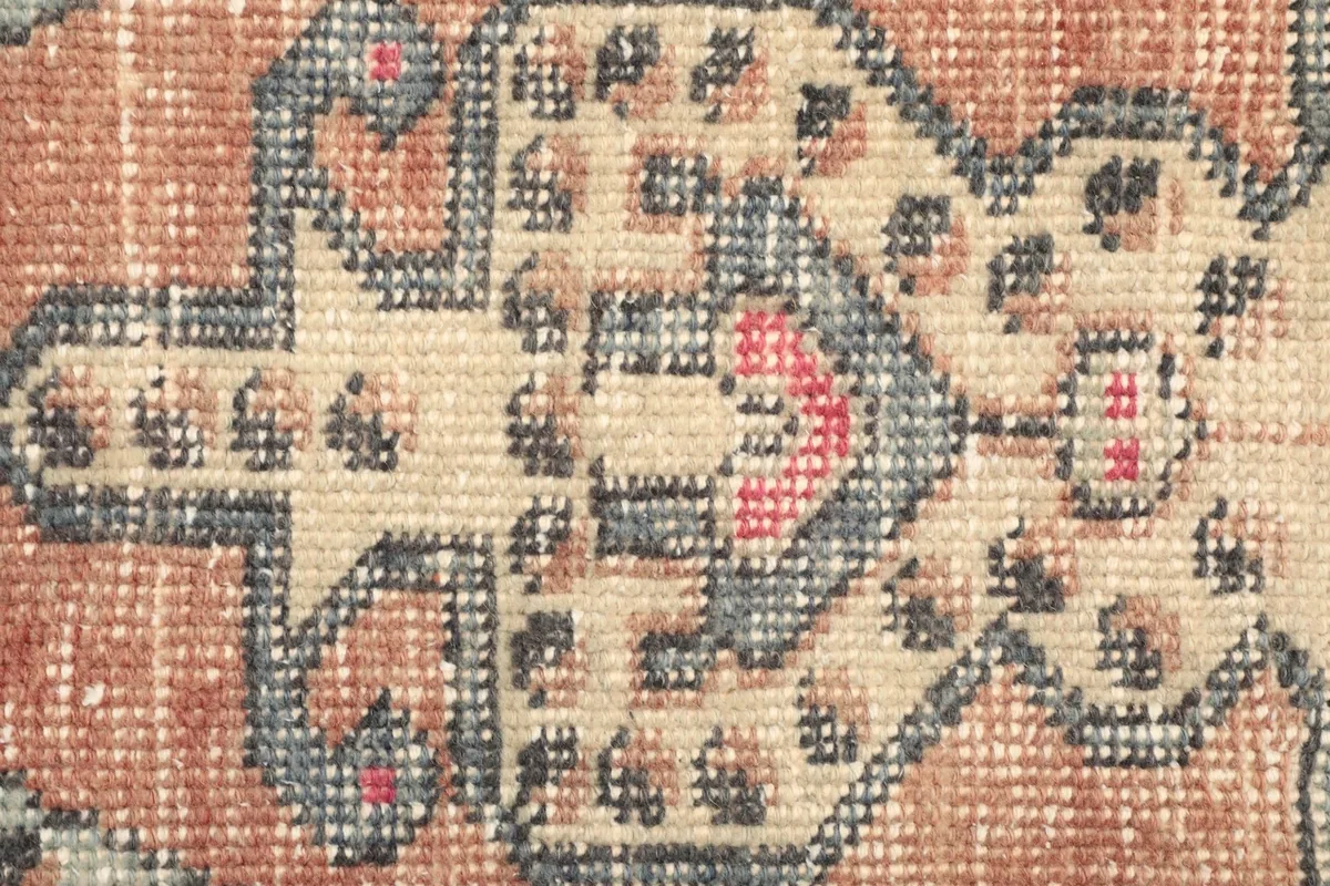 Close-up of a geometric motif within the rust field, showing wear and color variations
