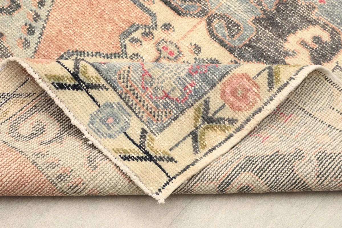 Corner of the rug folded back to show the hand-knotted construction and cotton foundation