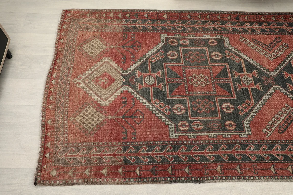 Angled detail showing the vintage patina and intricate border of the runner rug