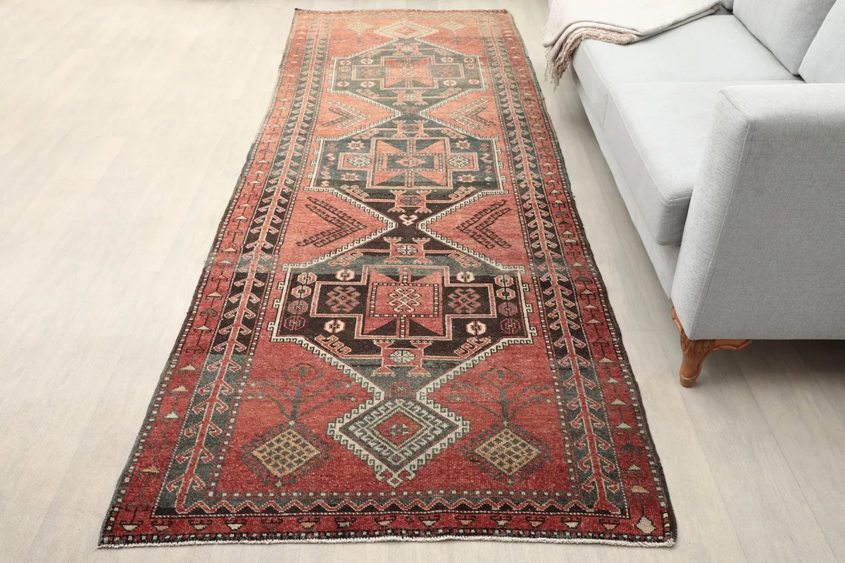 Rust and charcoal runner rug in a room setting next to a gray sofa