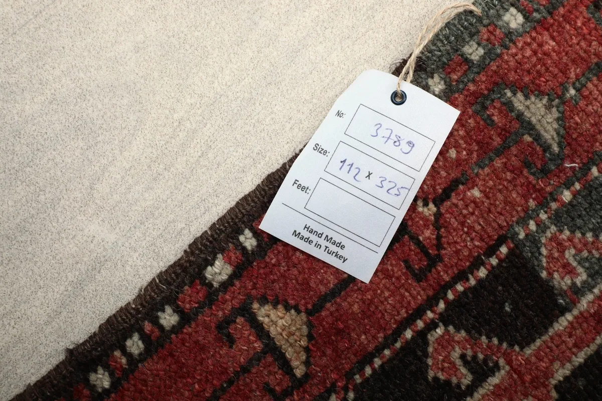 Back of the hand-knotted rug with a size tag showing 112x325 cm