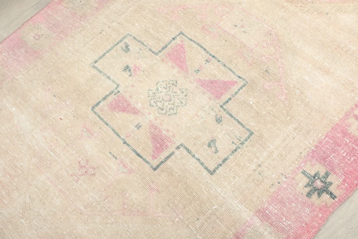 Macro view of a central geometric motif with rose and blue details on the beige field