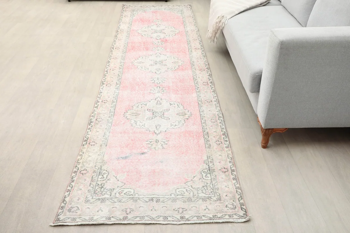 Vintage Anatolian runner rug laid out in a modern room setting next to a gray sofa