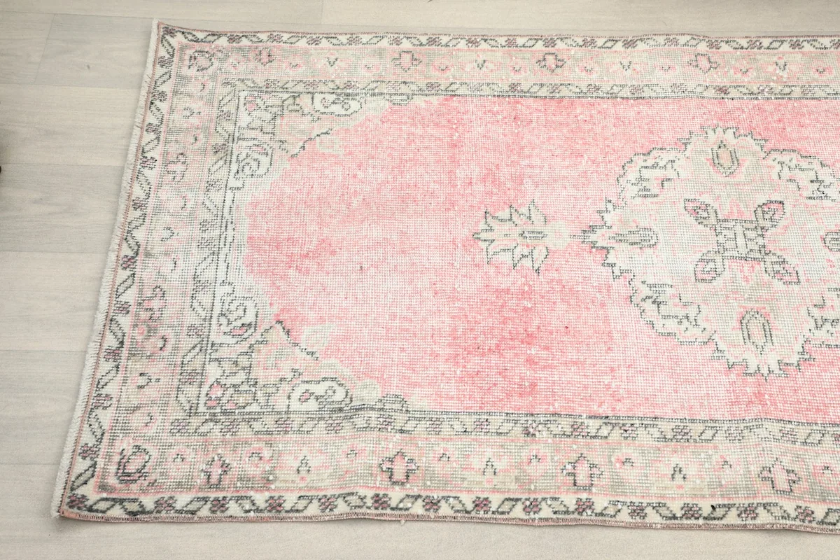 Detail showing the border design and part of the pink field with a medallion motif