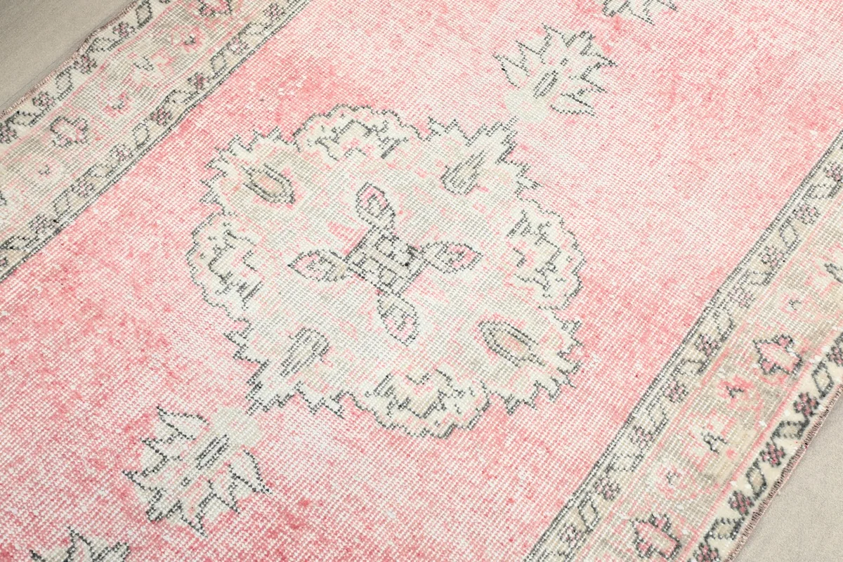 Overhead detail of a central medallion and surrounding patterns on the pink runner