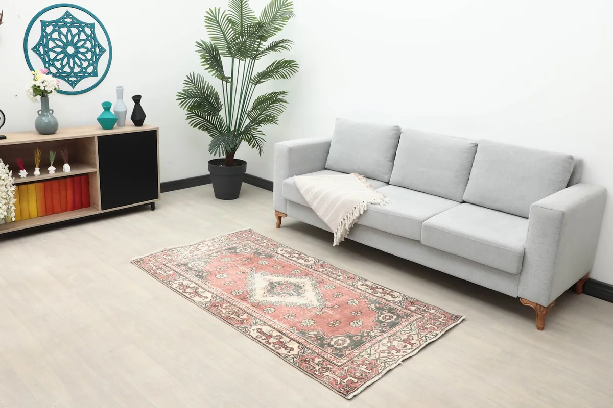 Full room view with the 3x6 rose geometric rug placed in front of a gray sofa and modern shelving unit.