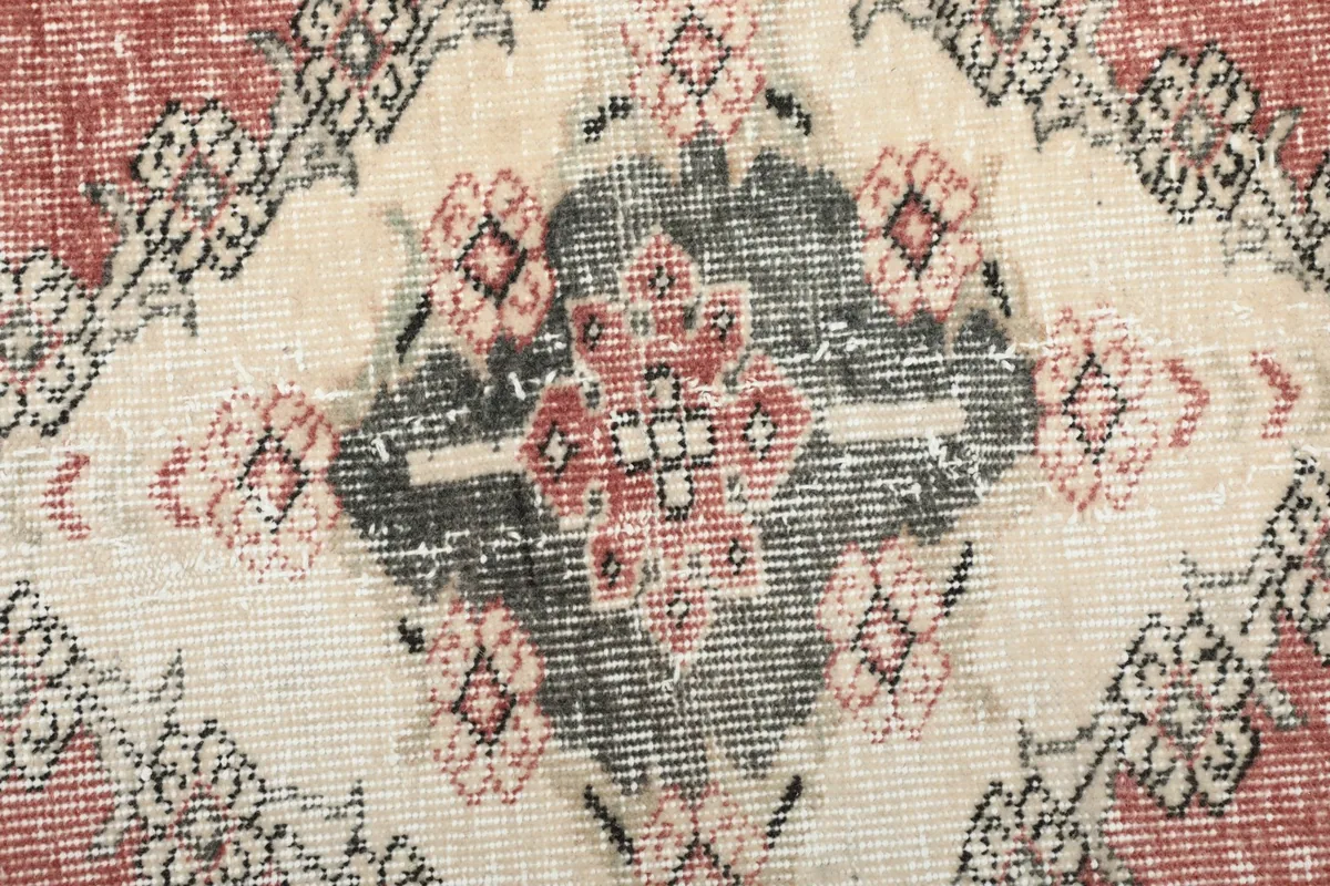 Macro detail of the central charcoal and rose medallion pattern with ivory accents.