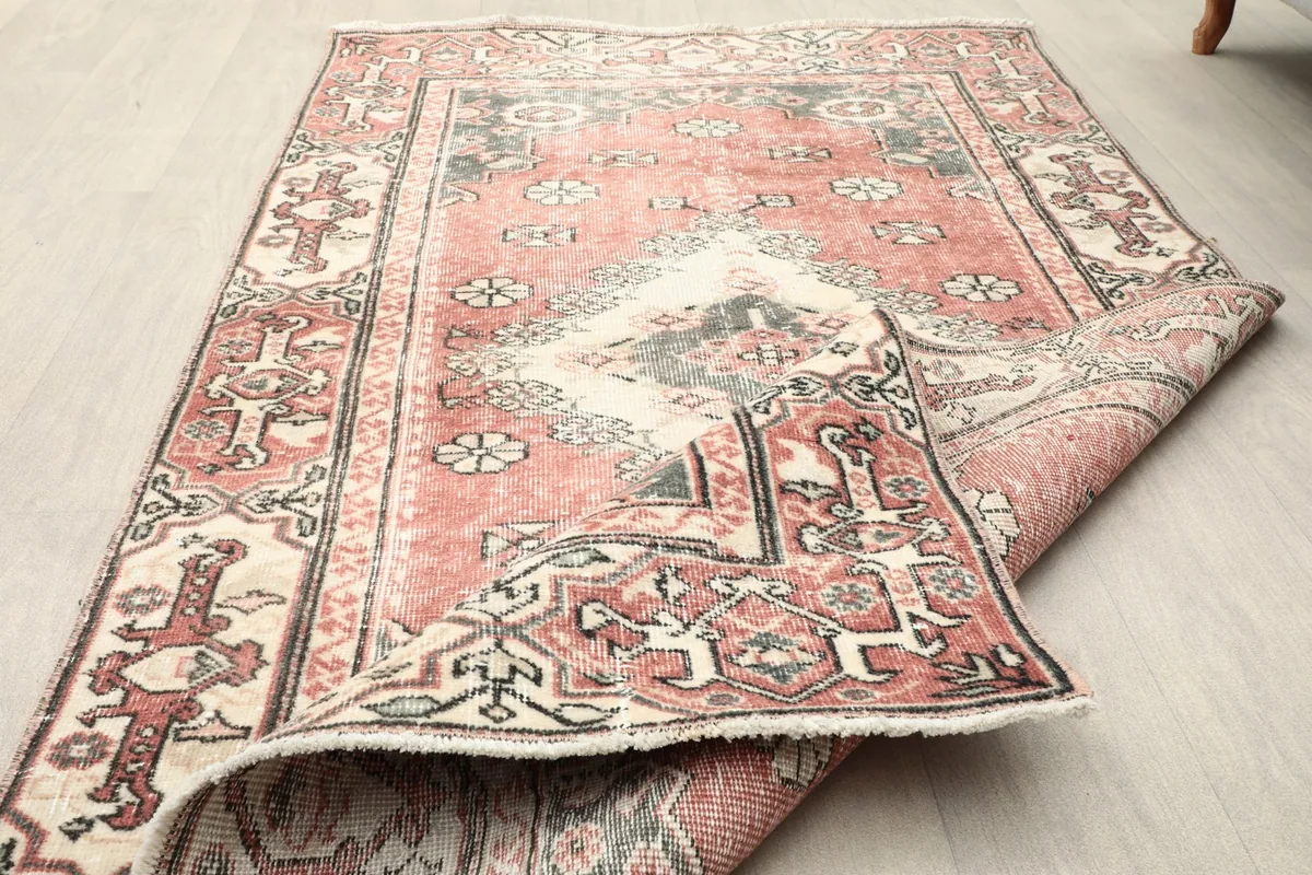 Partial fold of the rug revealing the intricate geometric patterns and original fringe.