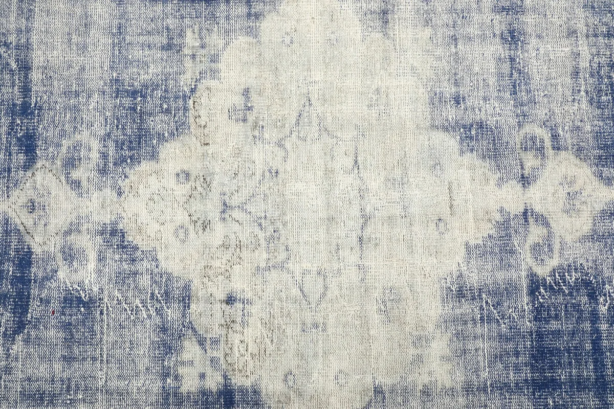 Close-up of the central cream medallion design with subtle patterns against the blue field