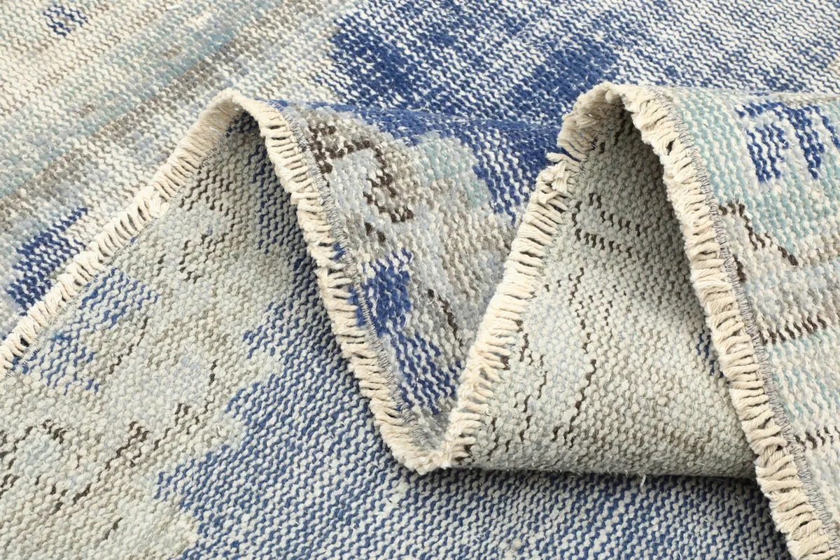 Close-up of the rug's folded edge, revealing the hand-knotted construction and fringe