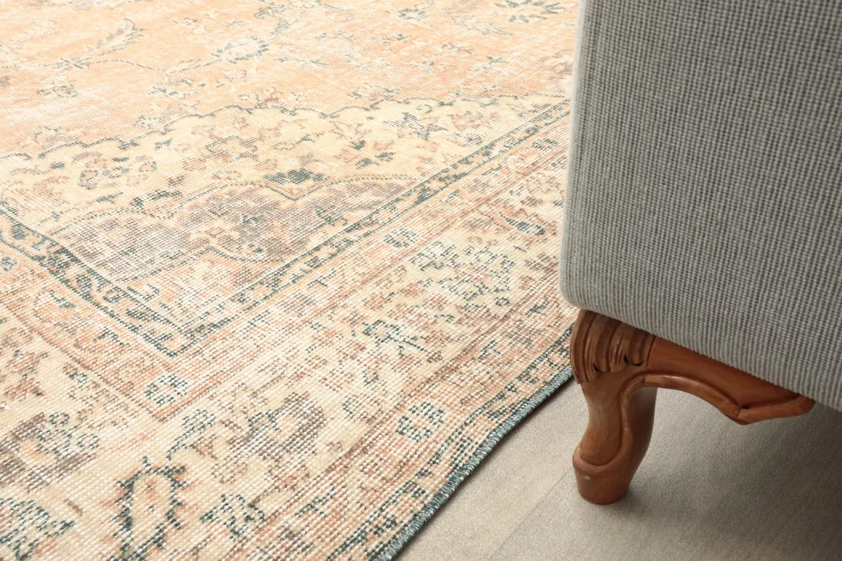 Close-up of the rug's border next to a sofa leg, showing how it fits into a living space