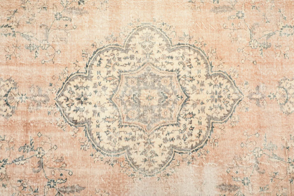 Detailed view of the central ivory medallion with blue and gray accents on the tan field