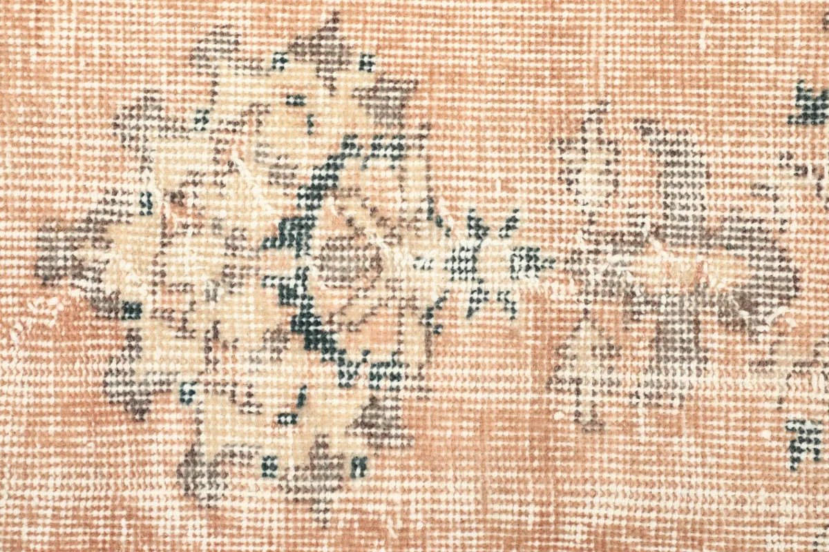 Close-up of the low wool pile, showing the texture and faded floral motifs of the vintage rug