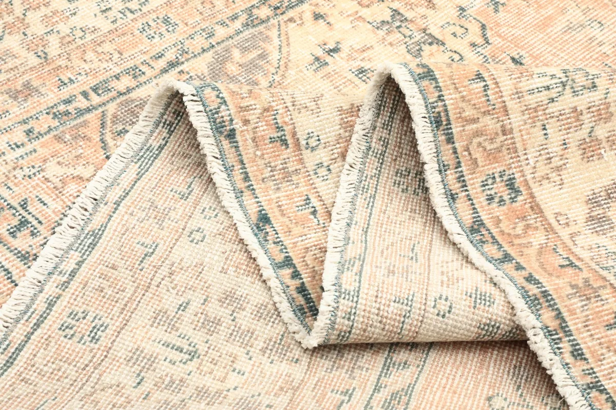 Folded section of the vintage rug, showing the wool pile and intricate knotting from the side