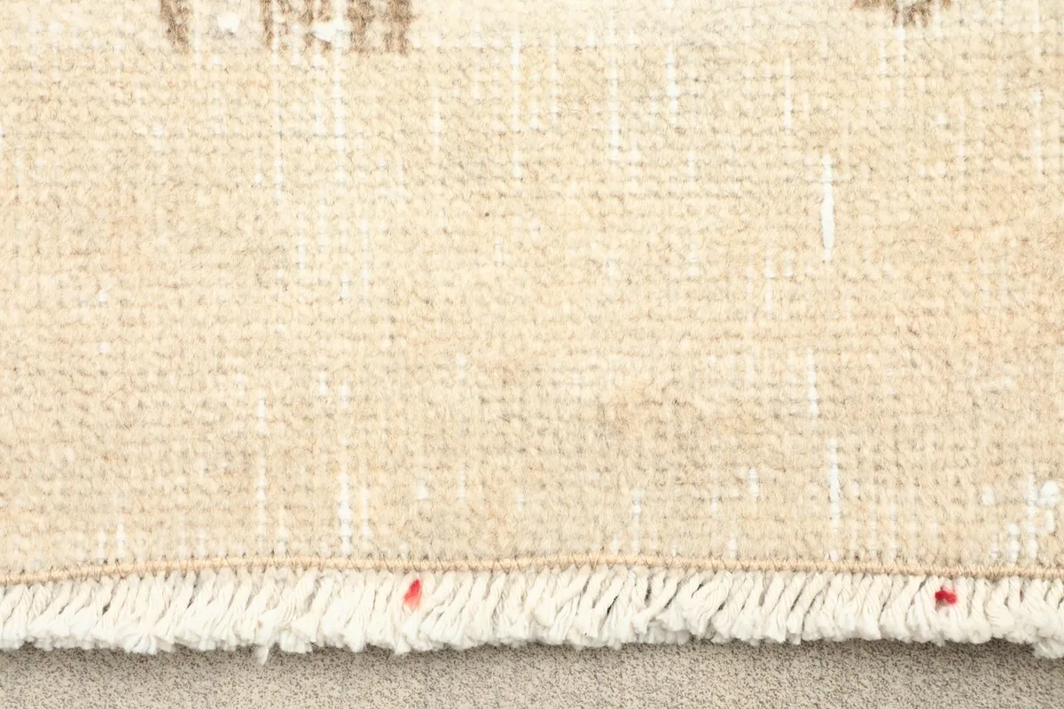 Close-up of the rug's short, natural ivory fringe and hand-knotted edge
